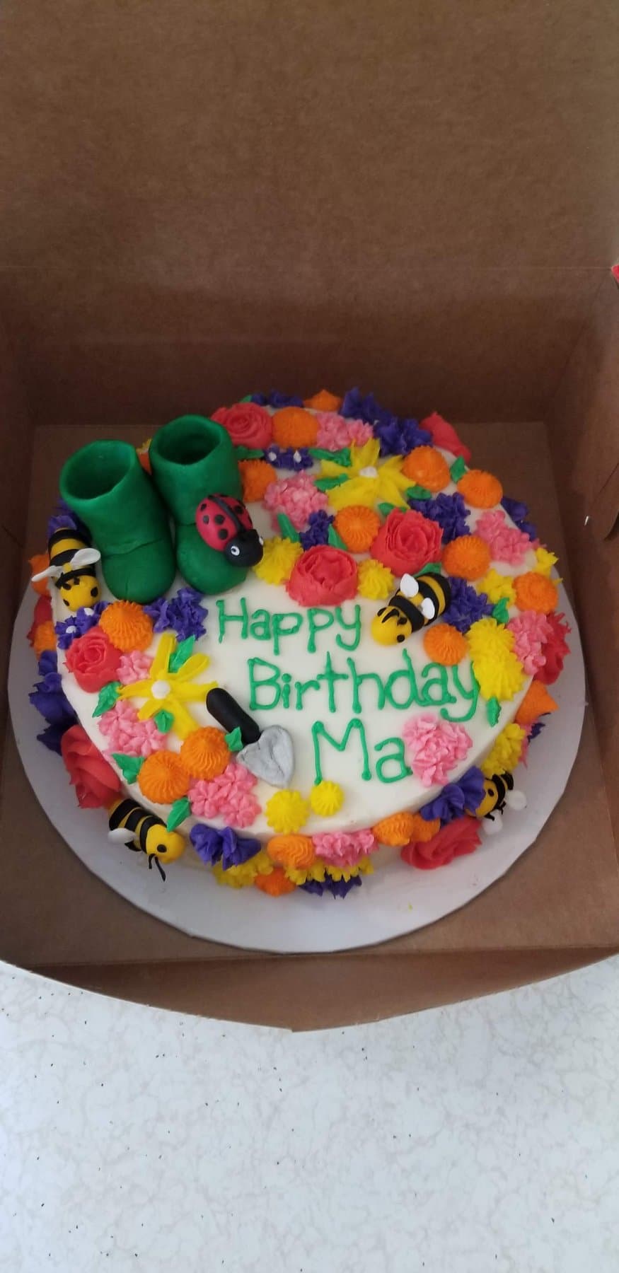 Garden-themed birthday cake with bright buttercream flowers and playful decorative accents by Jamie Cakes.