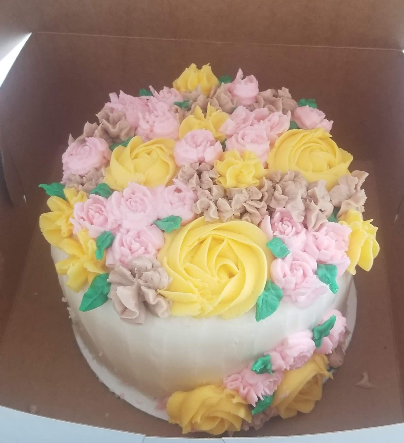 Pastel floral buttercream cake covered in yellow, pink, and lavender flowers by Jamie Cakes.