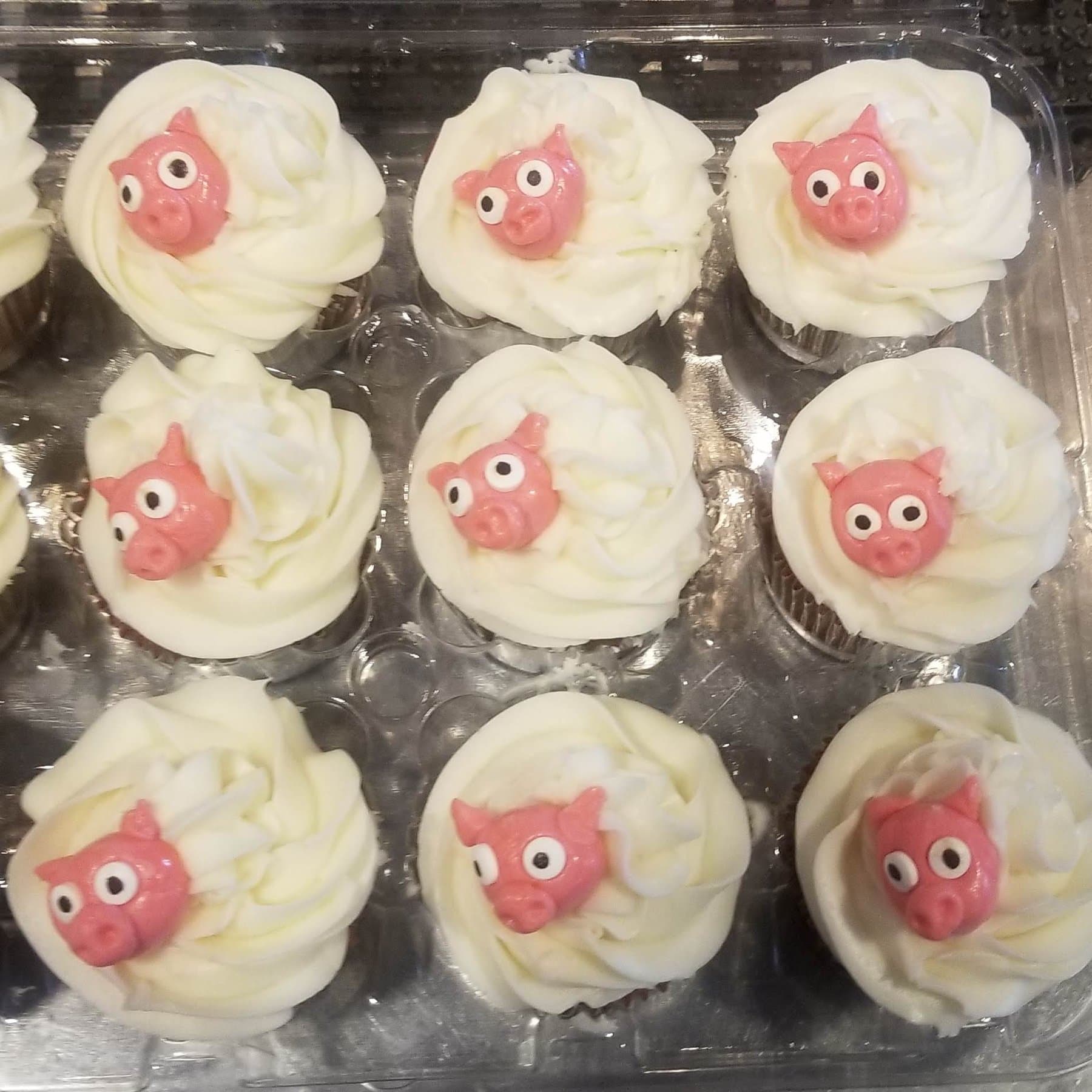 Pig face cupcakes with white frosting swirls by Jamie Cakes.